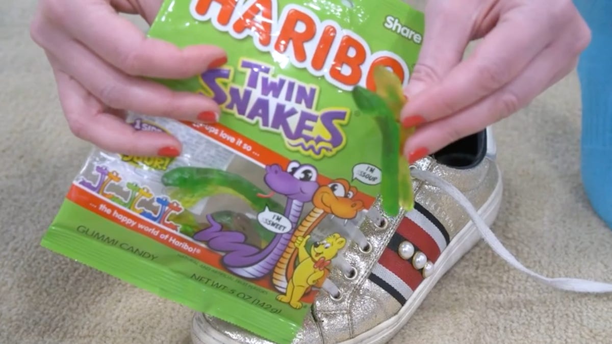 a bag of Haribo Twin Snakes being held up above a shoe