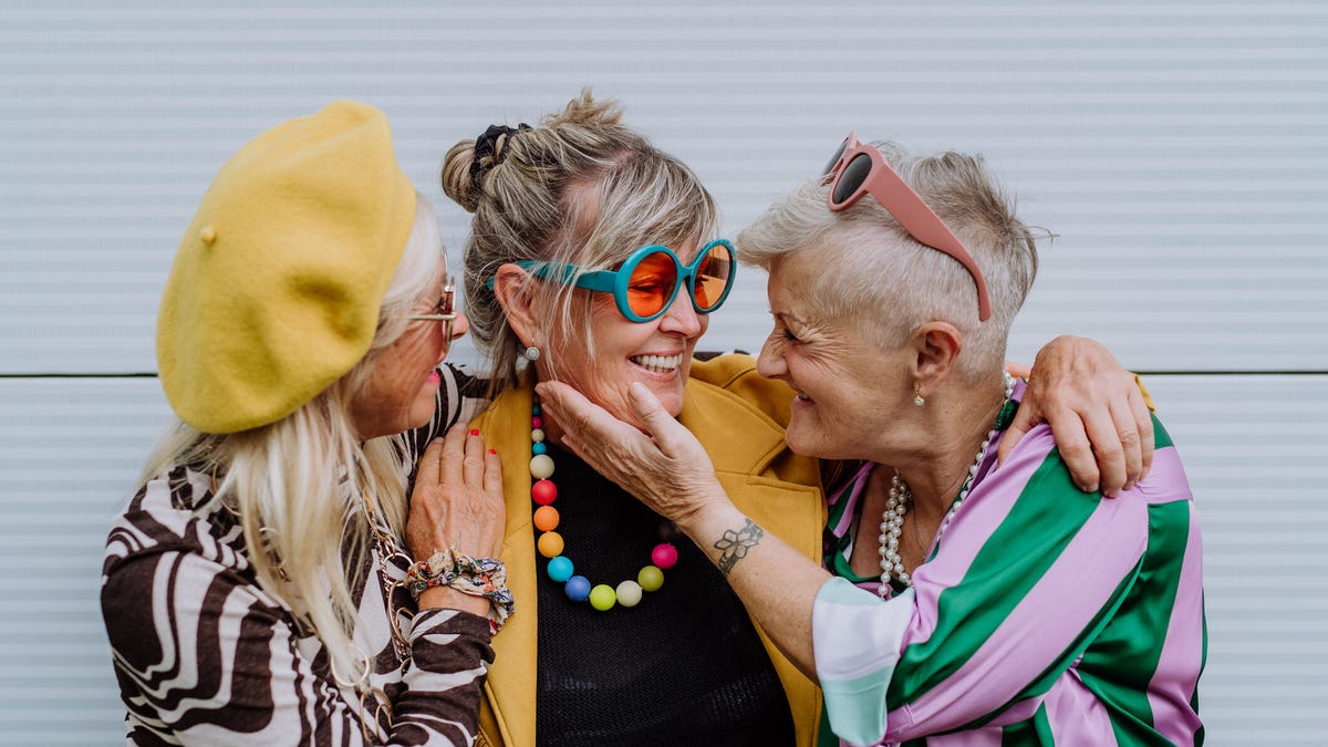 Three joyous older women embracing
