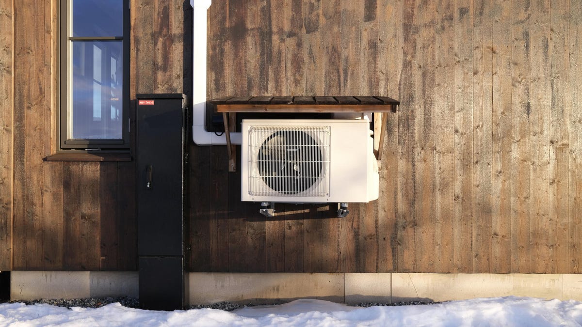 A heat pump on the side of a wooden building.