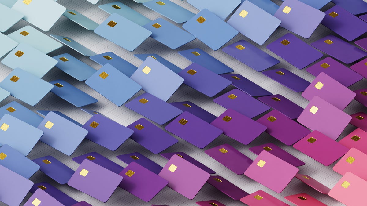 Multiple purple, blue and pink credit cards moving in a wave over a white background.