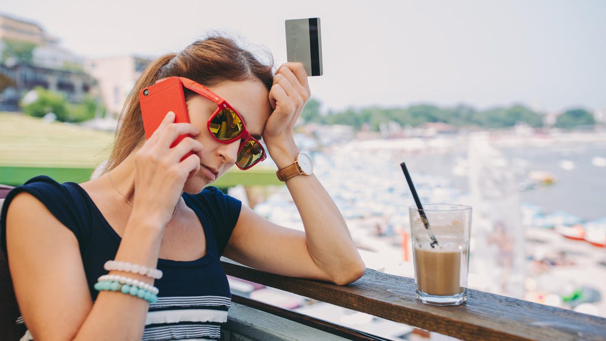 An image of a woman on vacation on the phone looking agravated.