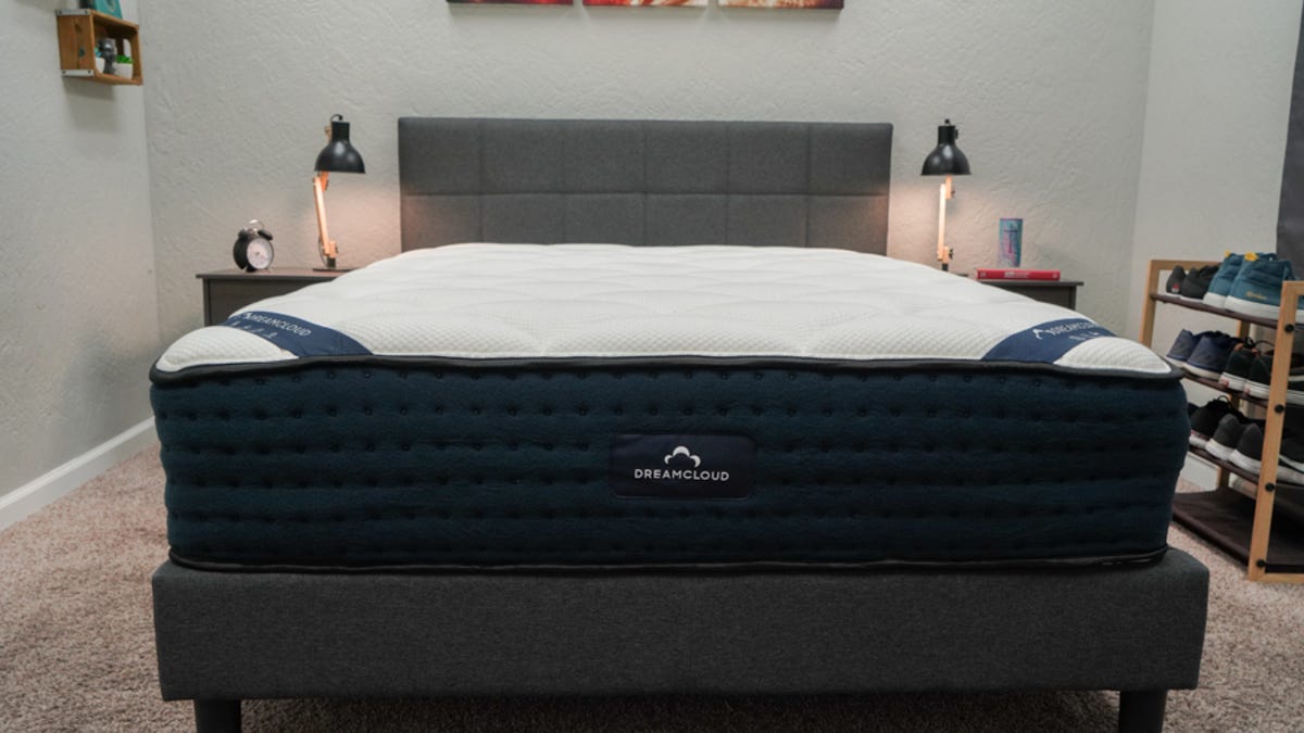 The DreamCloud Hybrid mattress on a gray bed frame with two nightstands next to it.