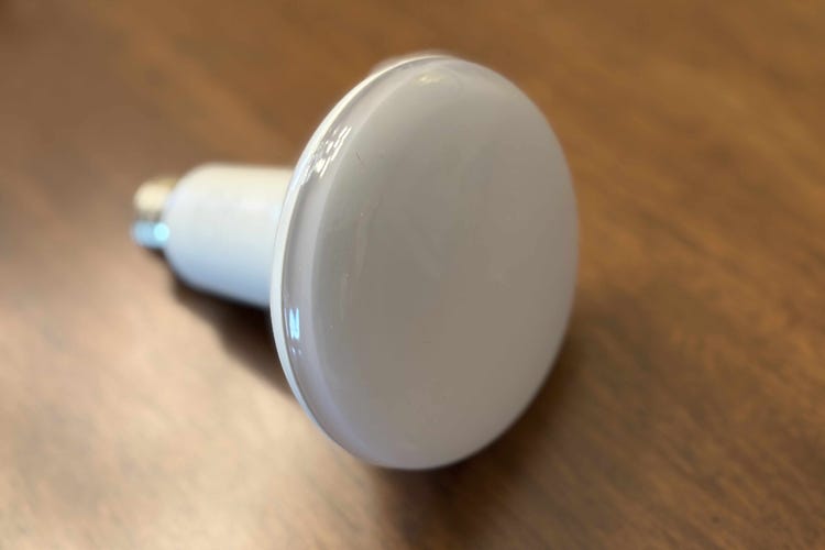 Philips dimmable LED floodlight bulb on a wood surface.