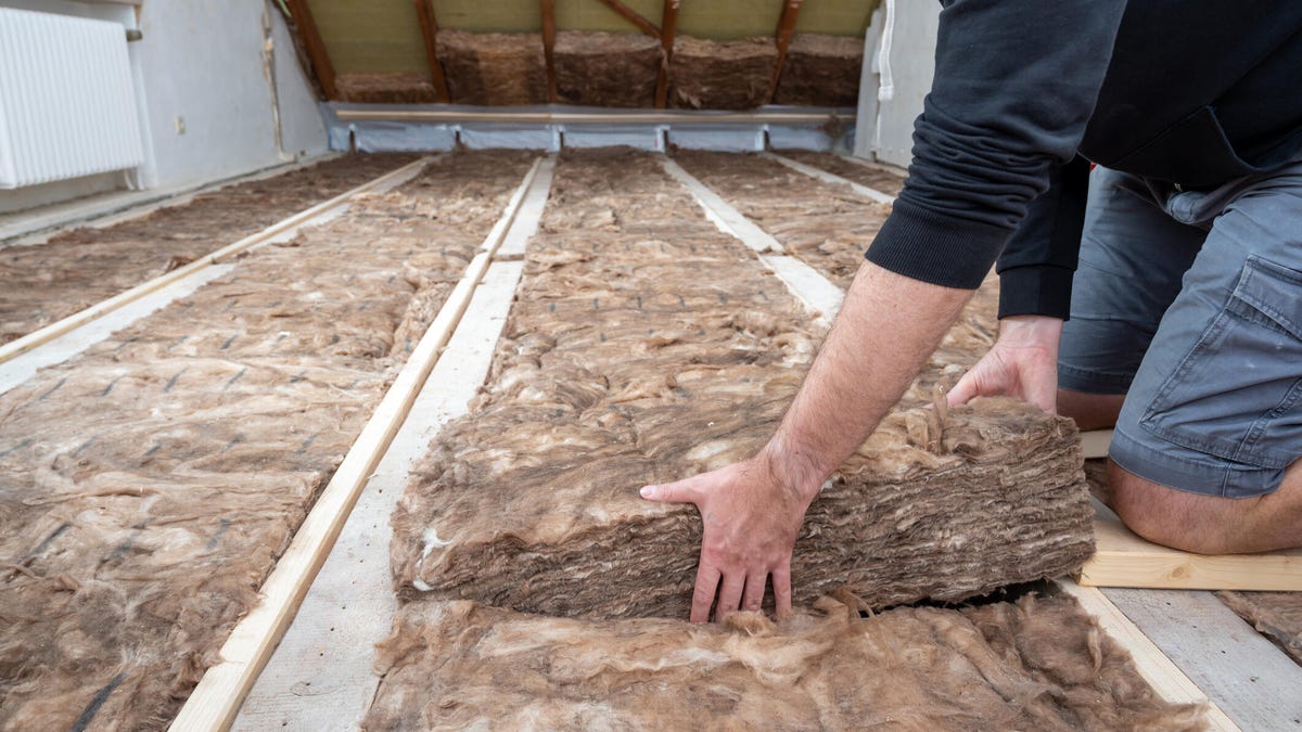 A person installs insulation in an attic.