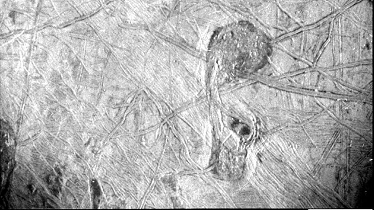 Odd-looking, striated icy crust Jupiter moon Europa with criss-crossing lines in black and white.