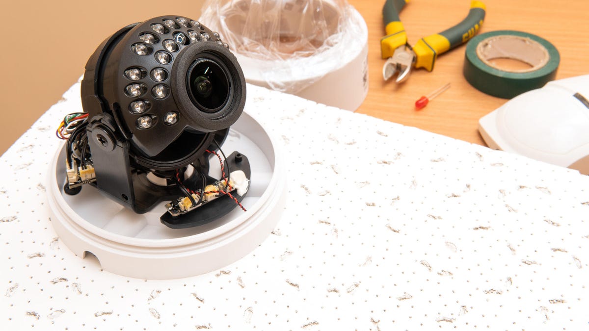 An opened security camera next to tools.