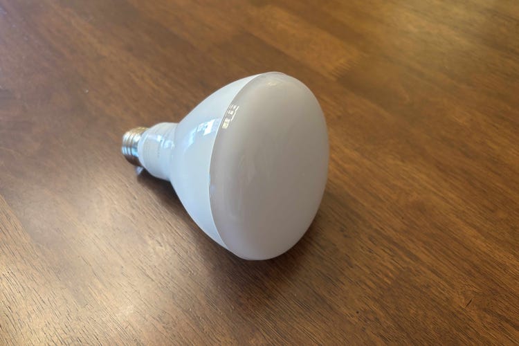 A Cync smart floodlight bulb on a wood surface.