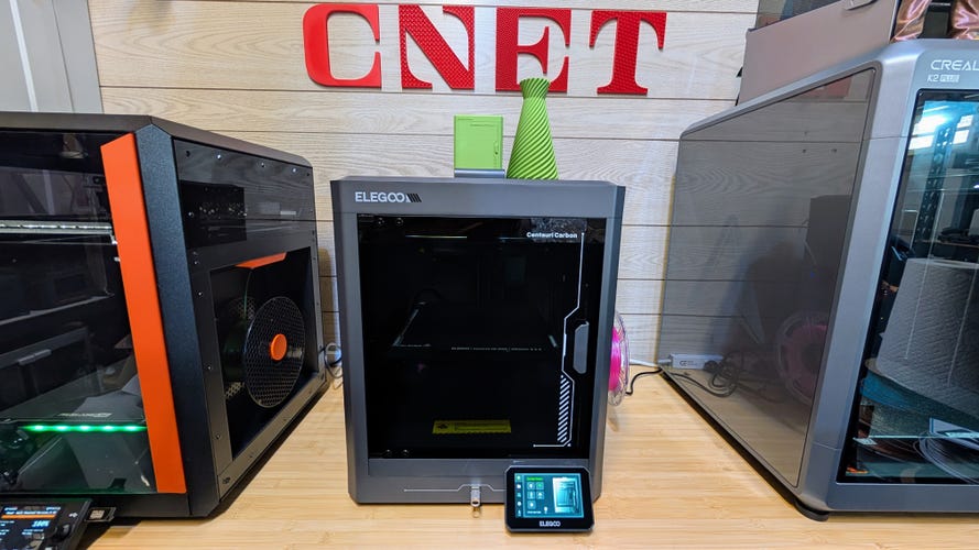 A grey 3D printer between two other prints and the CNET logo above it.