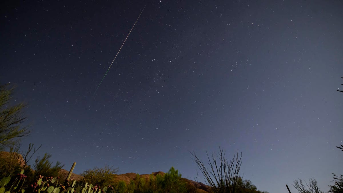 a shooting star streaks across the night sky