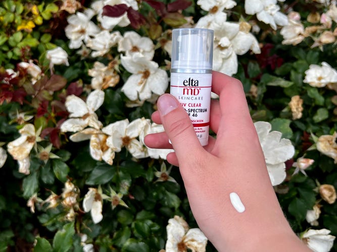EltaMD UV Clear Sunscreen on hand in front of flowery background.