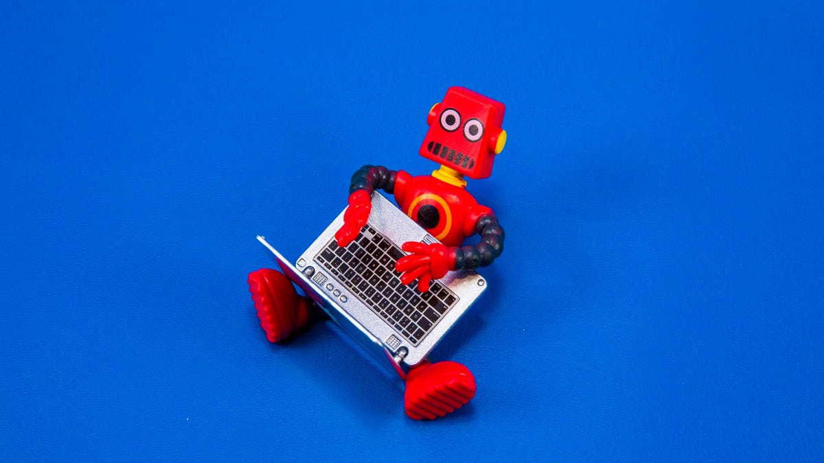 toy robot typing on a laptop