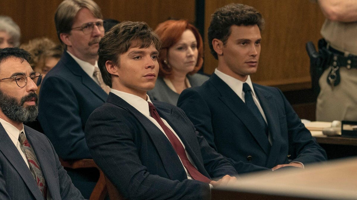 Men sit in suits at a courtroom table.