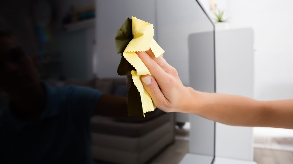 Cleaning a flat-screen TV with a microfiber cloth.