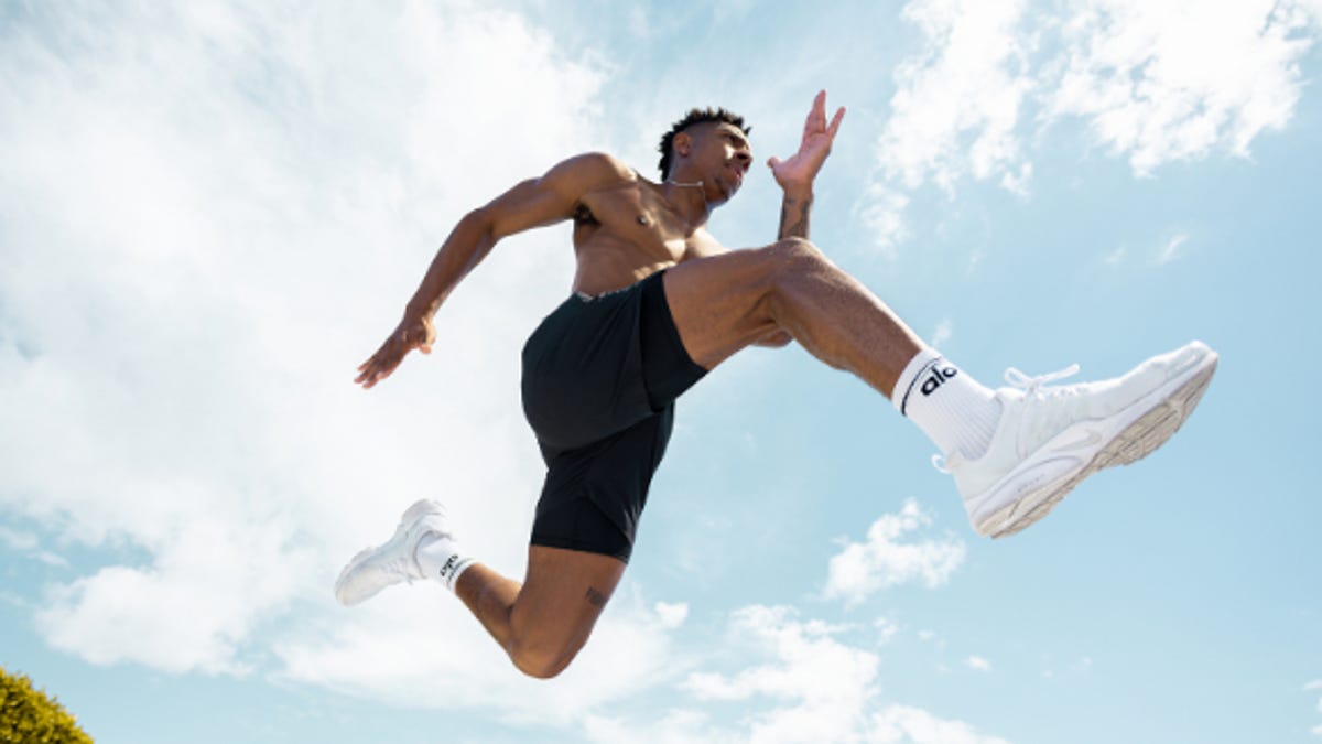 Man jumping mid air wearing black shorts and white sneakers