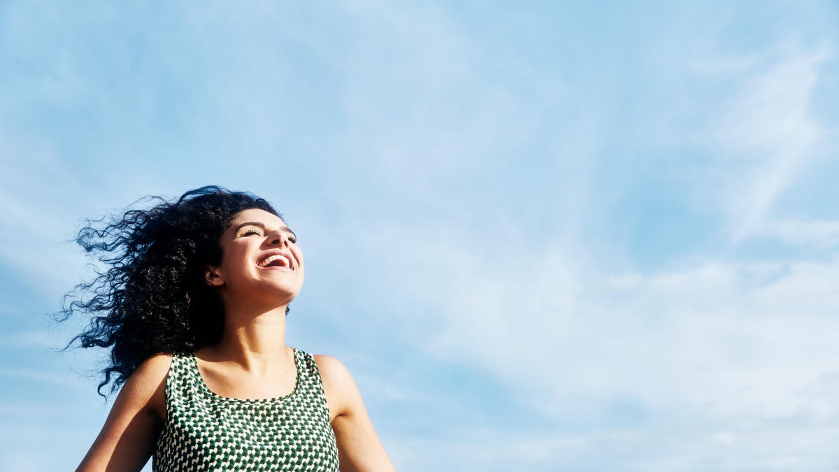 A young woman beaming while standing outside