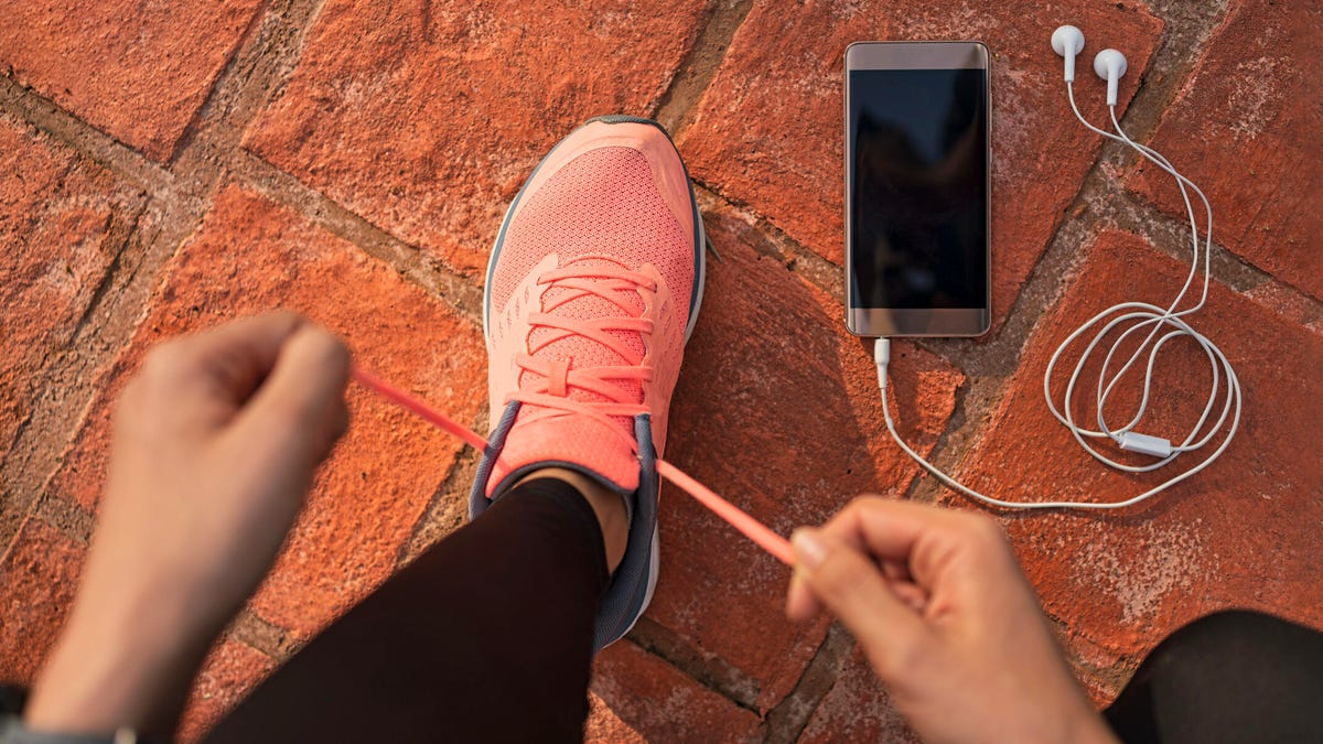hands lacing up a pink running shoe