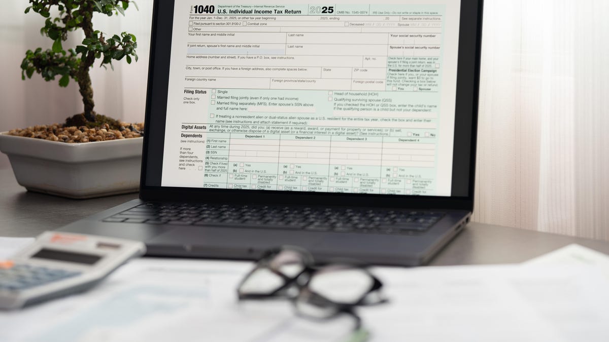 a laptop with the IRS website and the Form 1040 for 2025 sits on a table with a bansai tree next to it