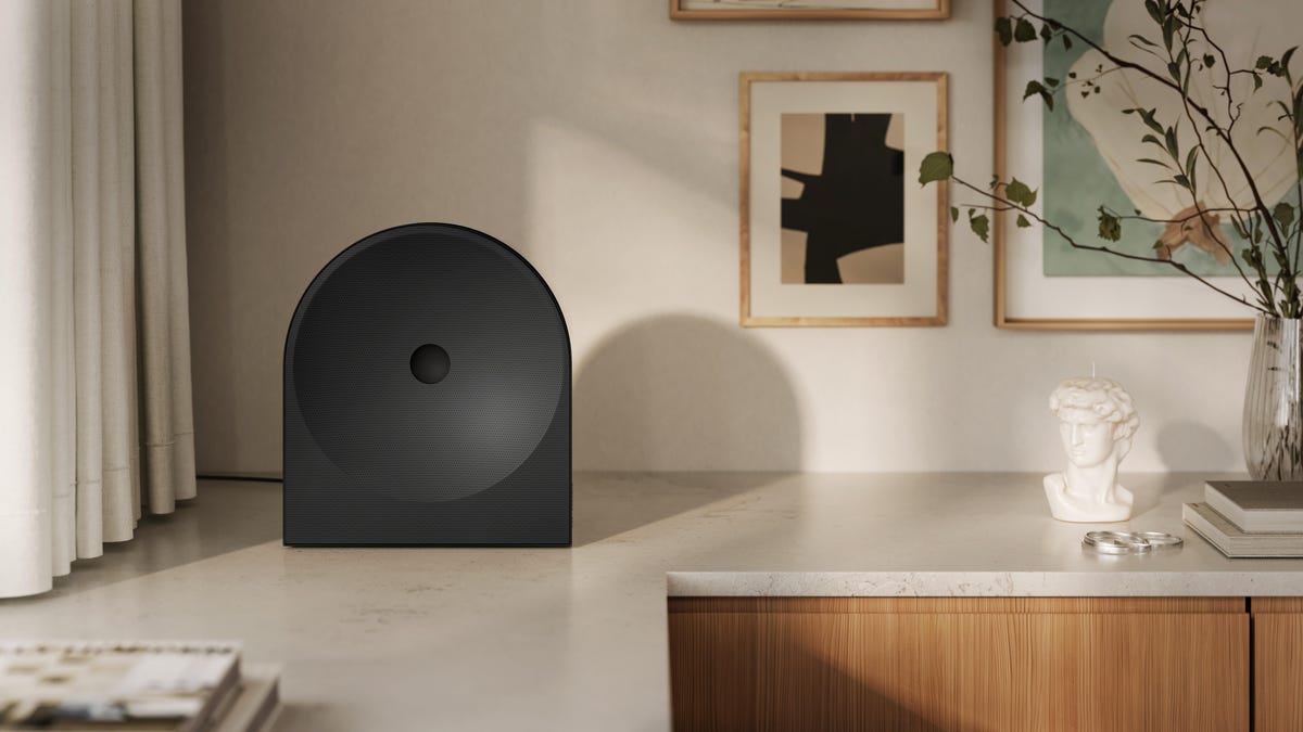 The black Samsung LS50H speaker sits at the corner of a light-colored table top.