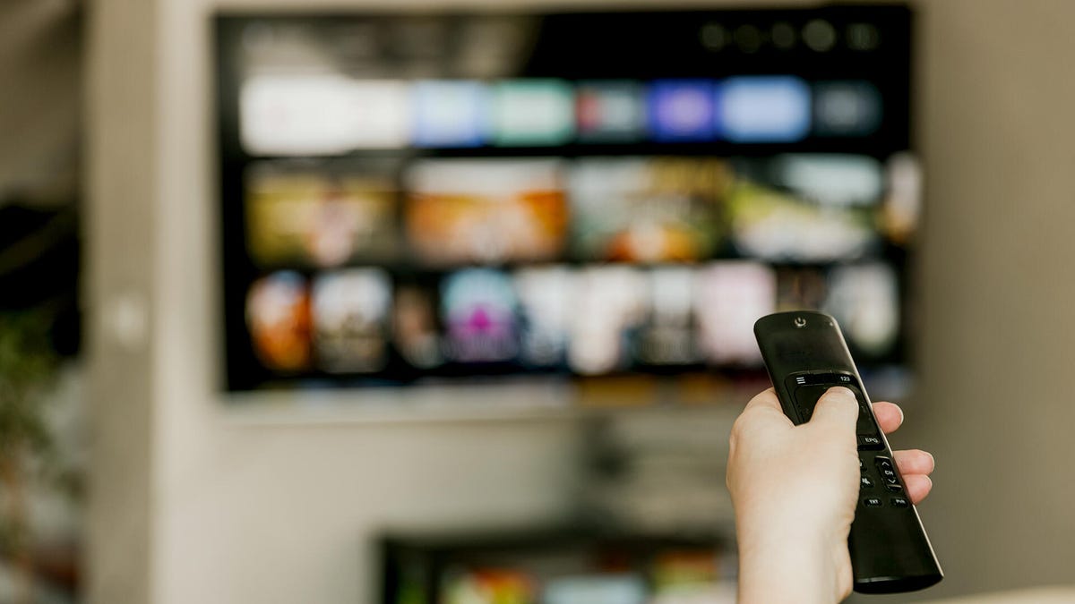 A TV on a wall with a remote in the foreground