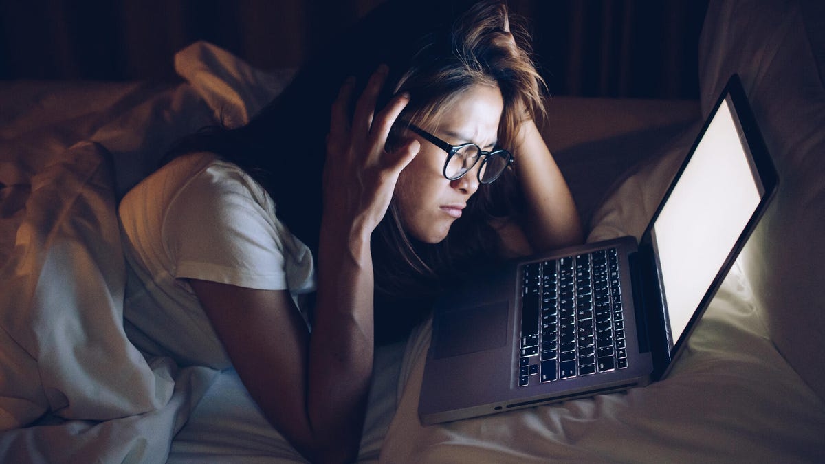 A woman staring at her computer screen up-close, stressed out