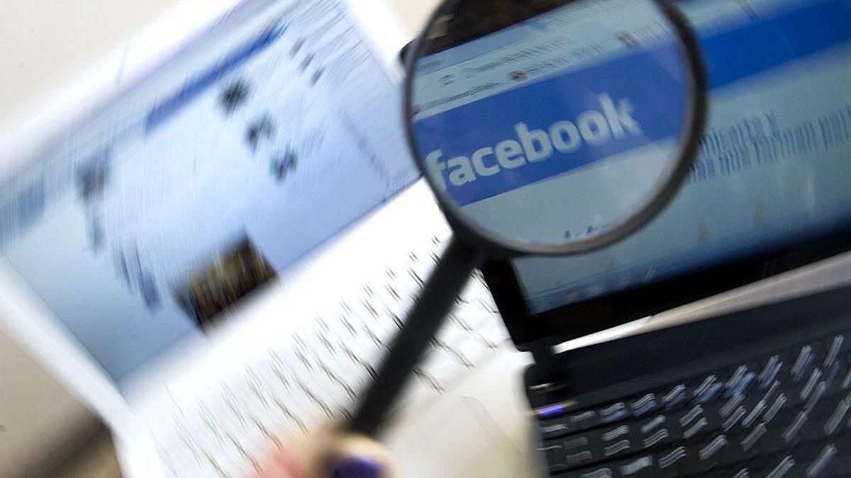 A magnifying glass held over laptops on Facebook, zooming in on the logo.