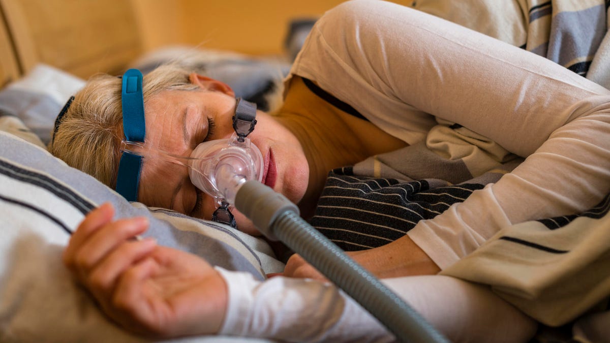 Woman sleeping on her side while wearing a CPAP mask.
