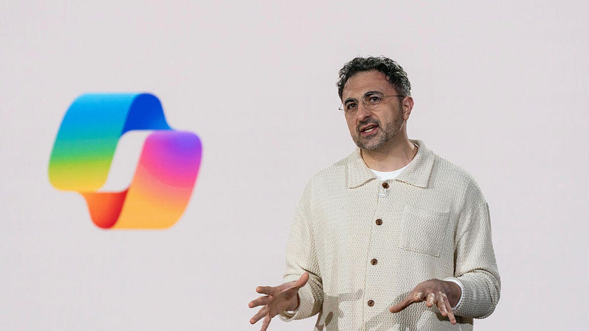 Mustafa Suleyman standing in front of the Microsoft Copilot logo