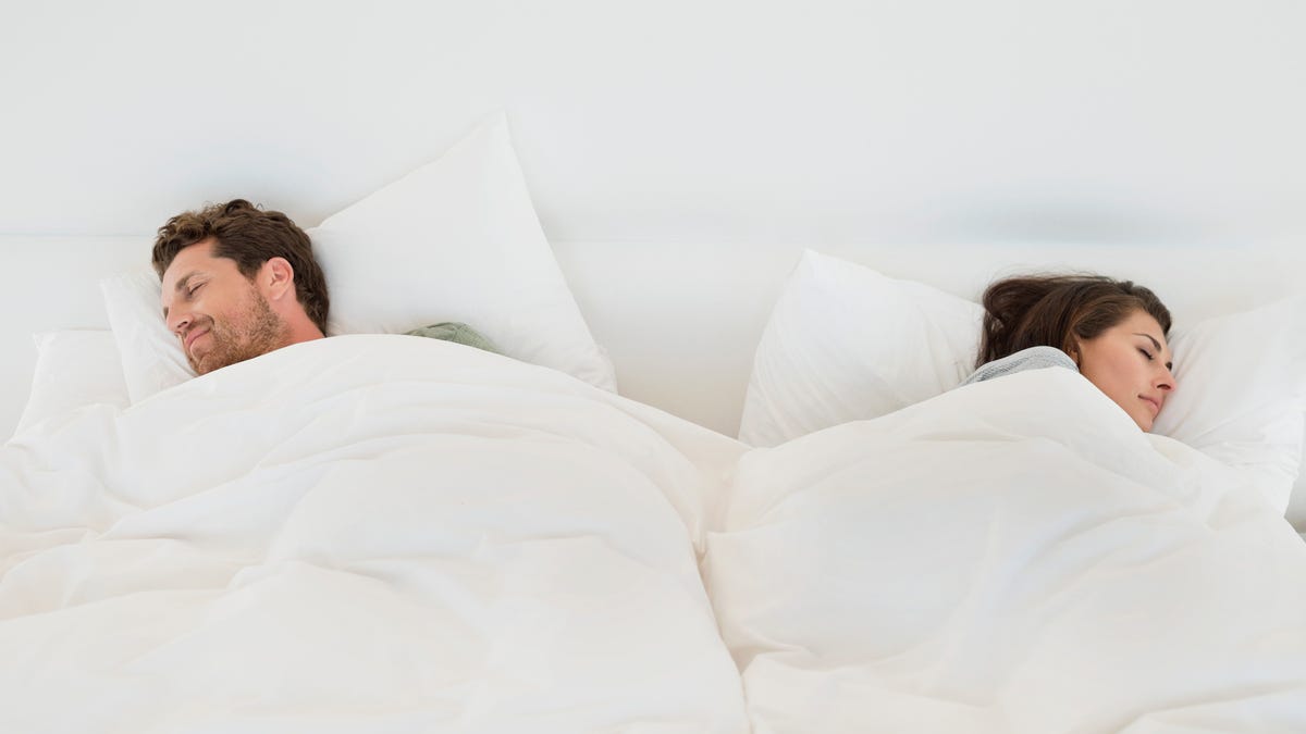 Man and woman sleeping with separate blankets.