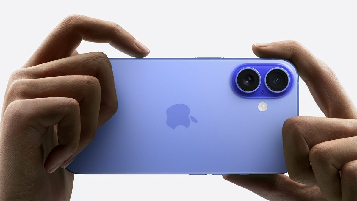 Close up of fingers holding an iPhone 16, with the index finger pressed on the Camera Control button.