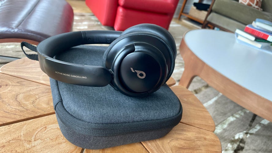 Black Anker SoundCore Life Q30 headphones sit on top of its carrying case on a wooden table. 