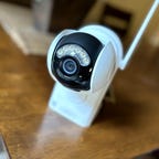 A Reolink Argus PR Ultra cam sits on a wooden table.