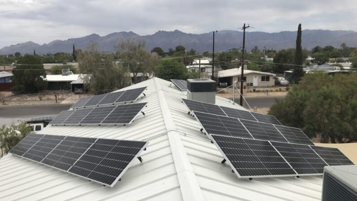 Solar panels on a white roof with mountains in the background.