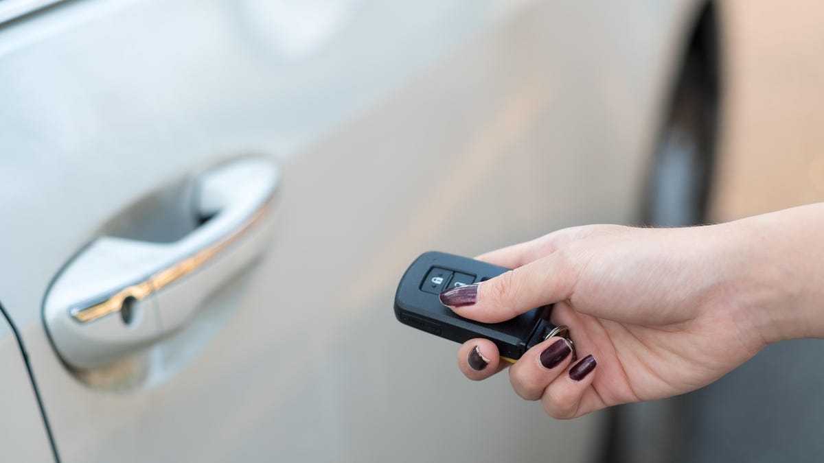 person holding an electronic key fob next to a car door