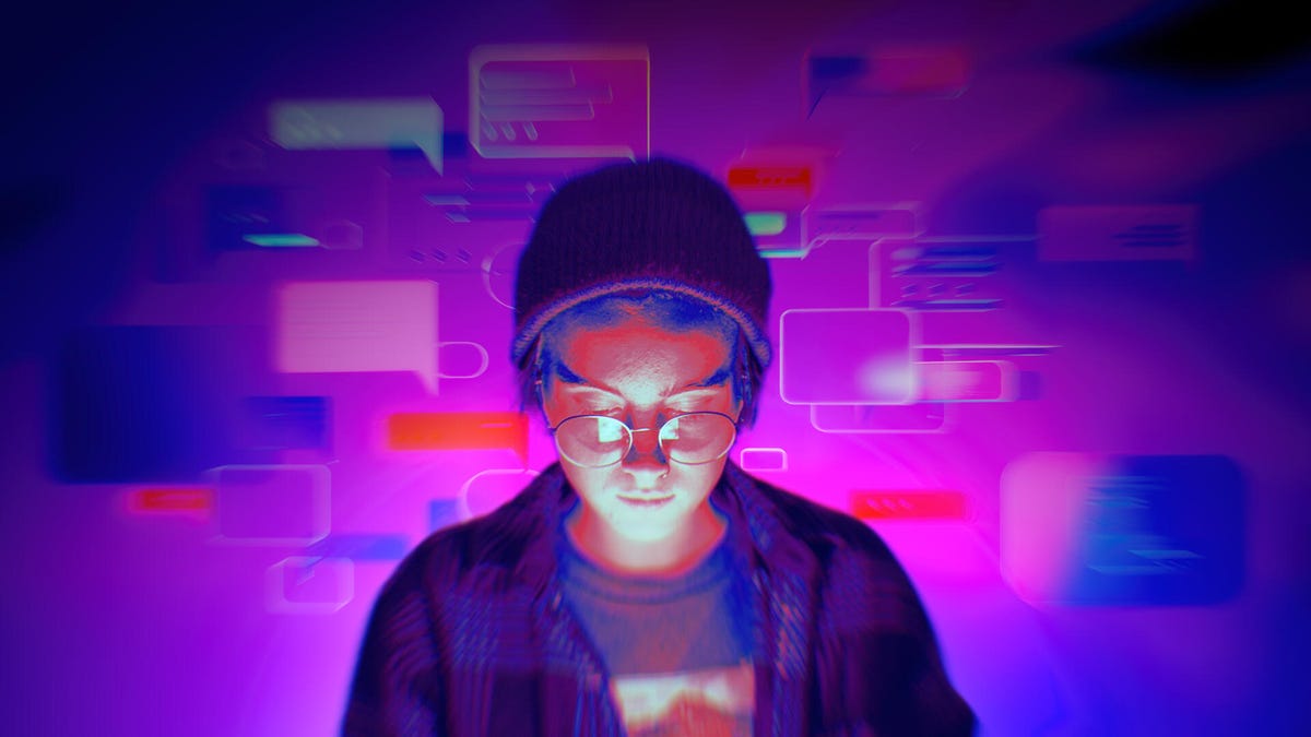 A person looks down at a handheld device. Chat boxes float in the air behind them.