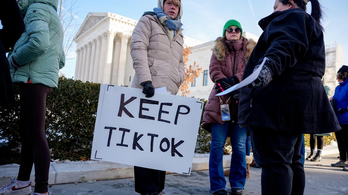 News photo shows a supporter in a parka, knitted cap and scarf holding a homemade sign that reads "Keep TikTok."