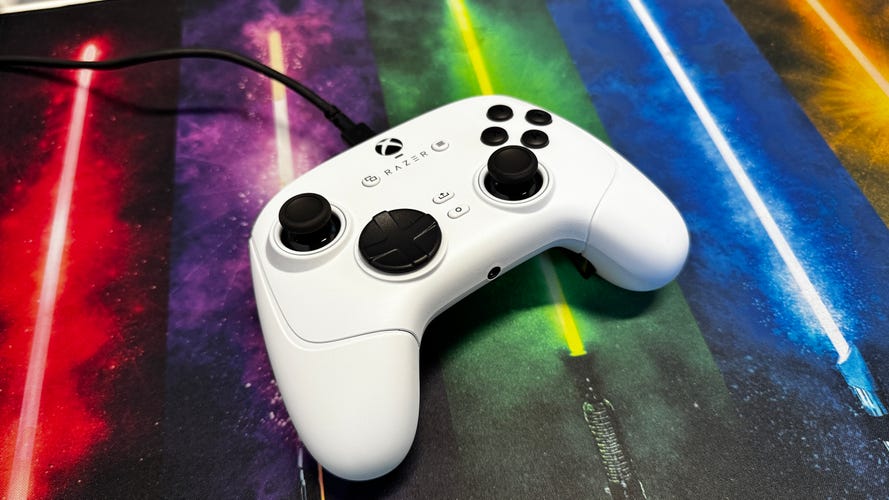 White wired Wolverine V3 controller laying on a desk mat with lightsaber design