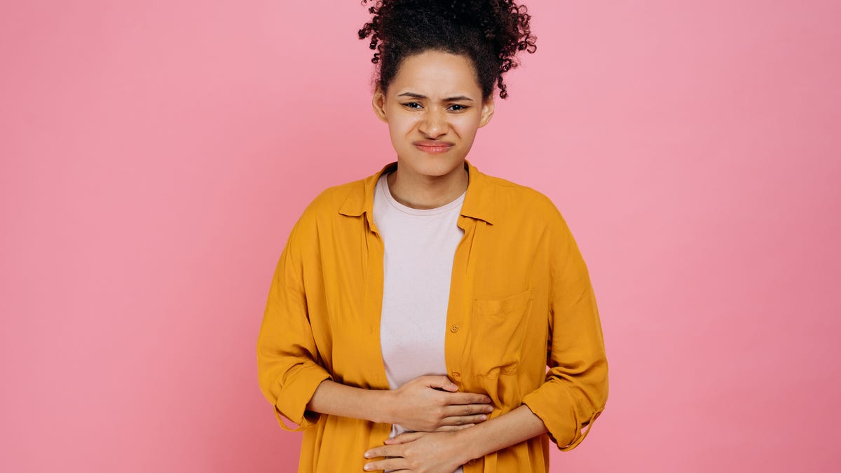 Woman with her hands on her stomach with an uneasy face.